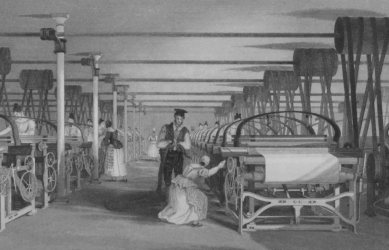 Une salle de tissage mécanique en 1835 : de longues rangées de métiers identiques, des tisseuses à chacun d'eux, et au plafond un arbre de transmission d'où descendent les courroies.