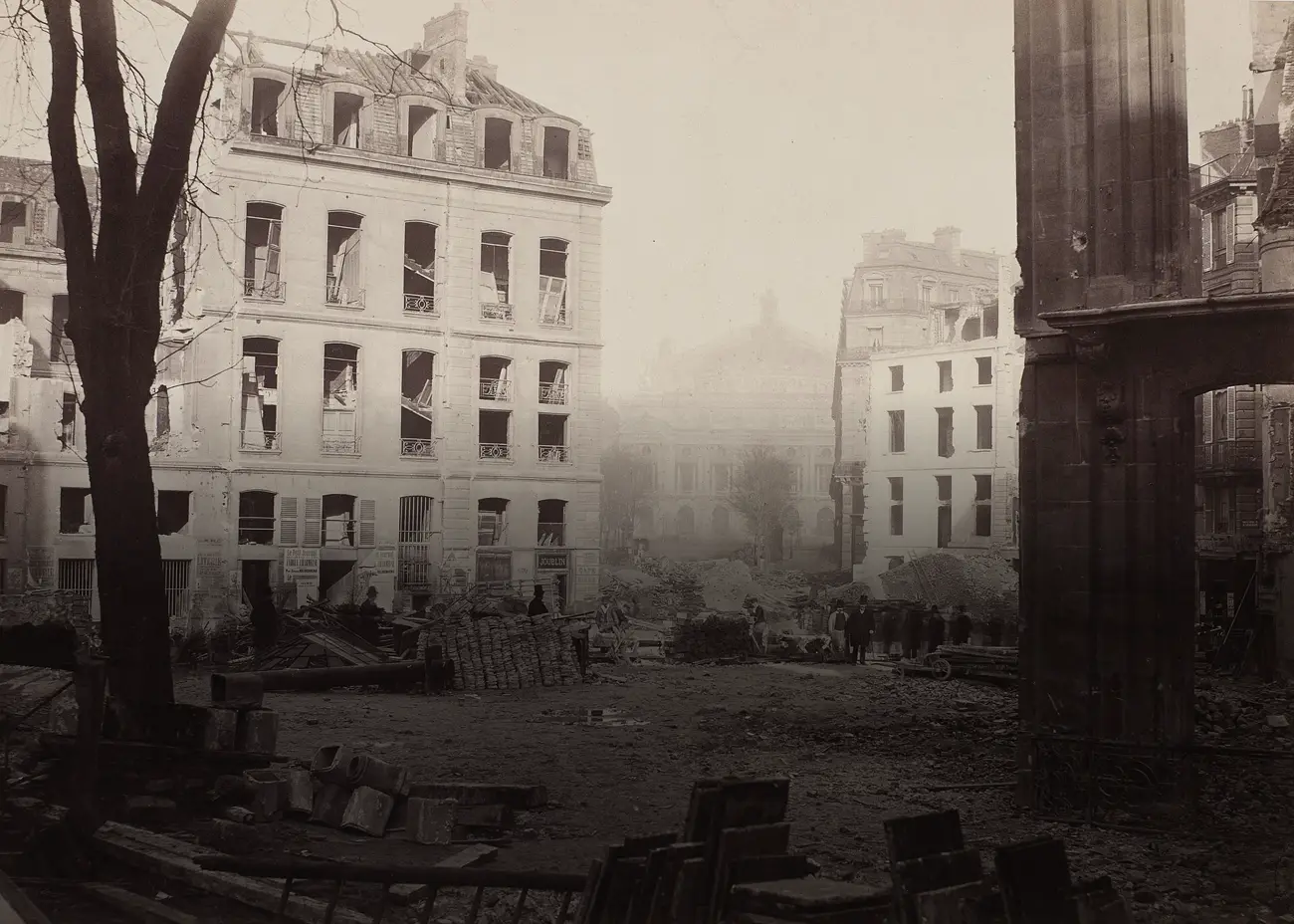 Un chantier de démolition à Paris : à gauche un immeuble aux fenêtres arrachées, au sol des gravats, des tuyaux et des piles de matériaux, des hommes en chapeau haut-de-forme qui se tiennent au milieu ; au fond, dans la brume, la façade de l'Opéra.